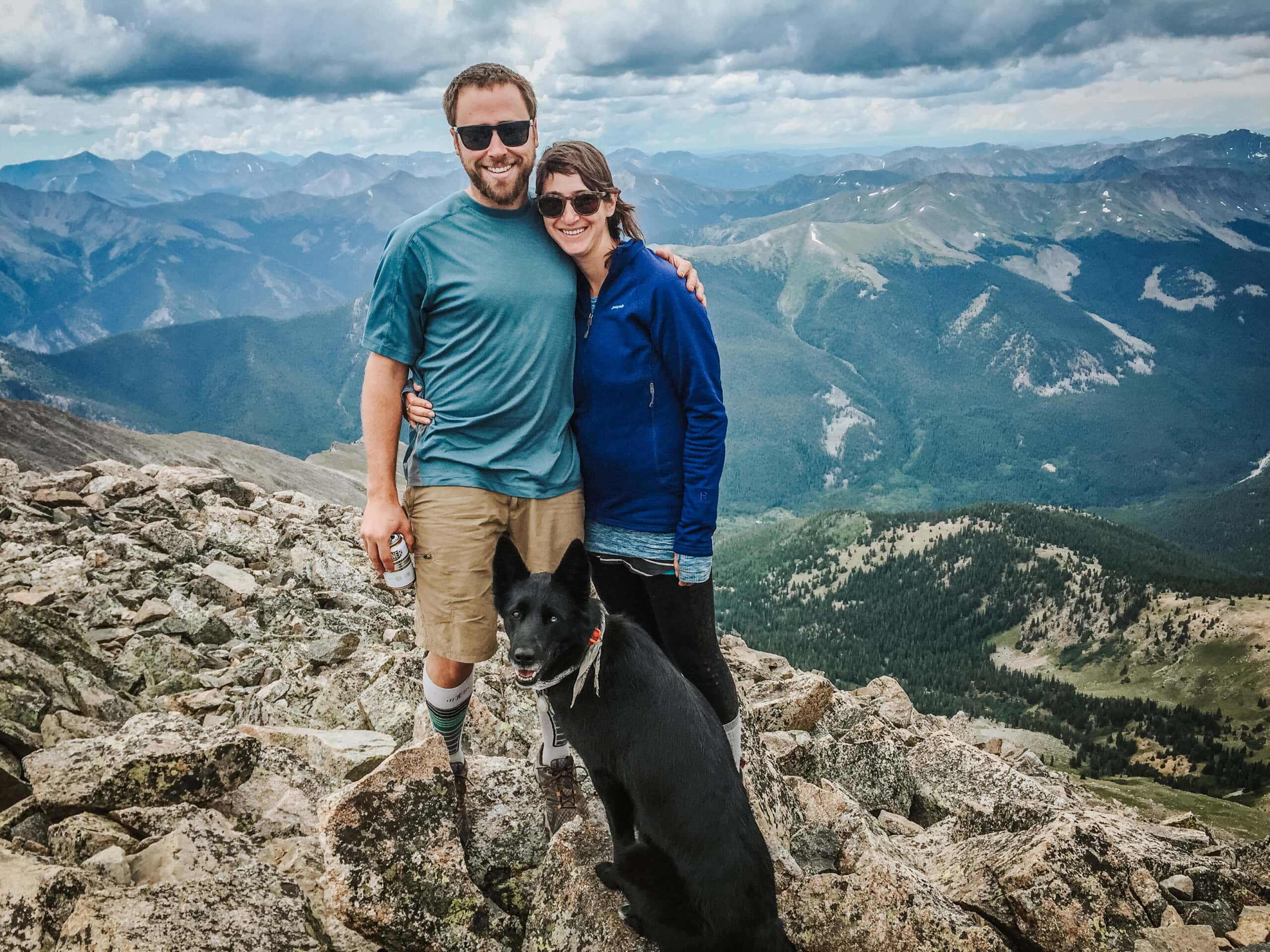 Two people and a dog at the summit of a 14er