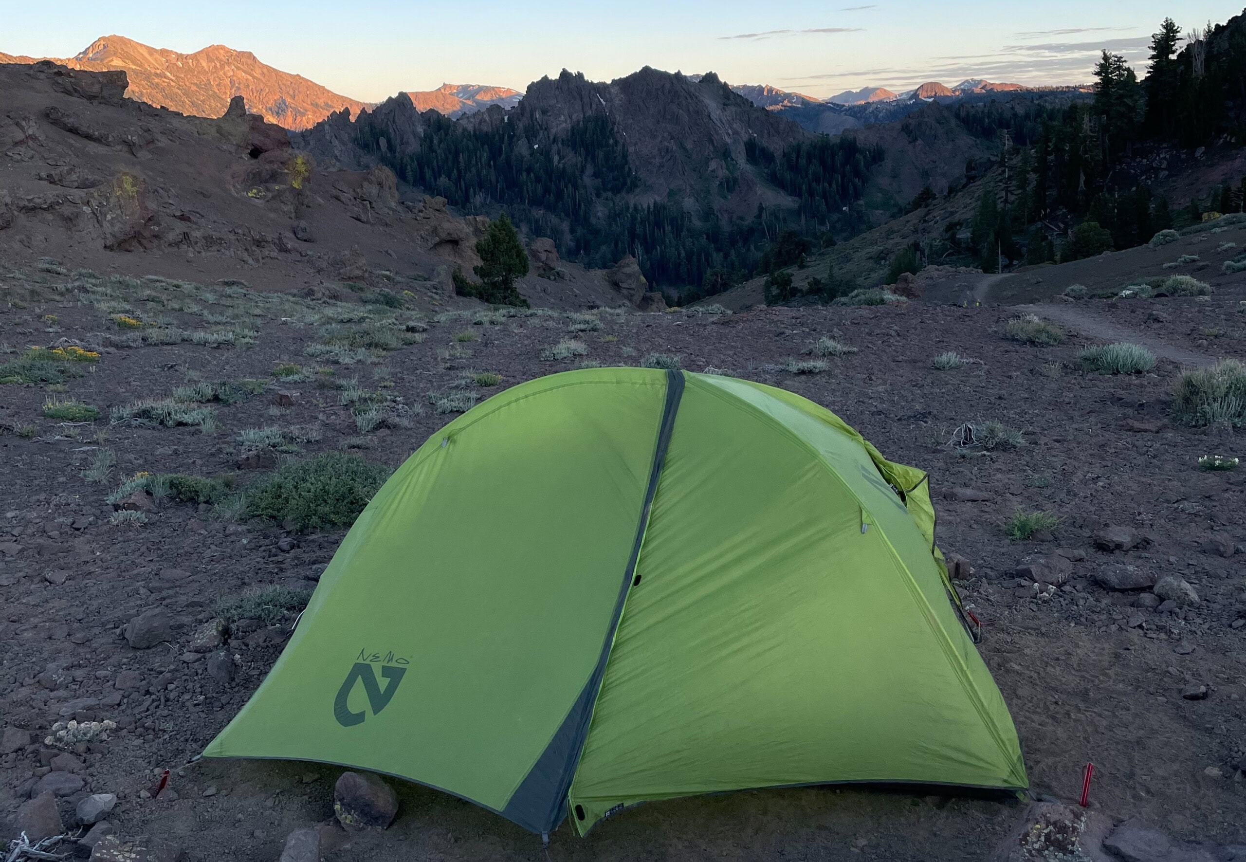 Bright green tent pitched in desert with mountains in the background