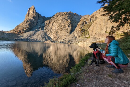 Dog and woman looking out onto serene lake